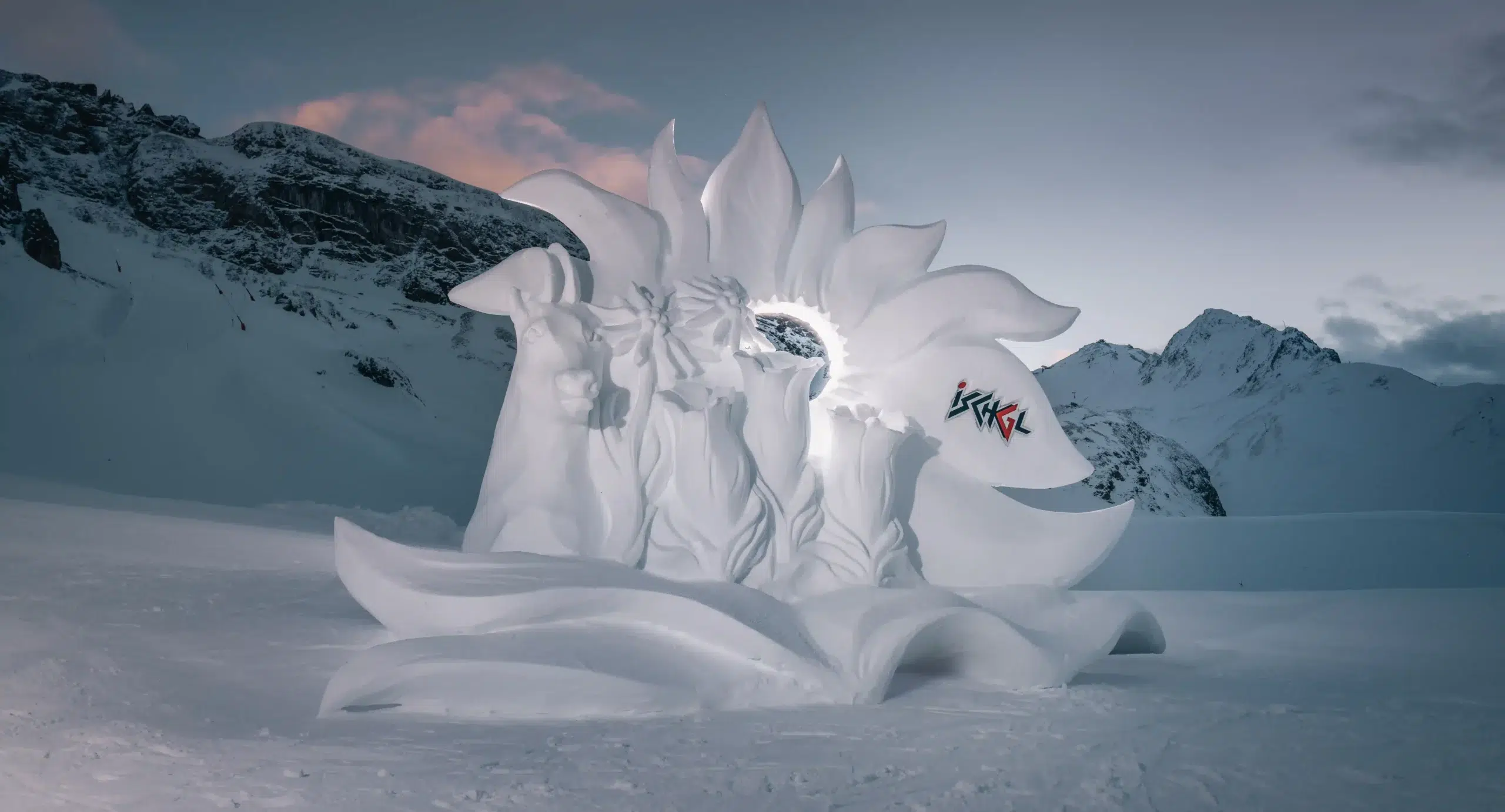 Aufwendige Winterschneeskulptur, die abstrakten Blättern und Gesichtern in einer verschneiten Berglandschaft ähnelt.