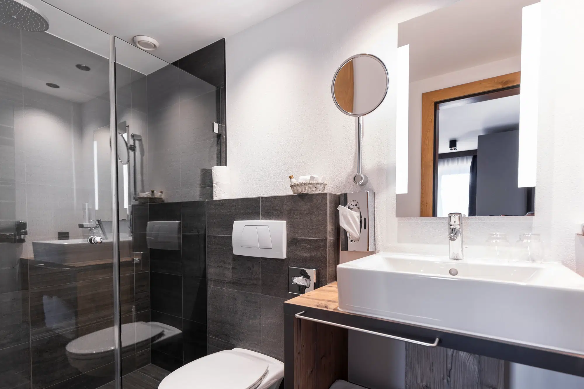 Modernes Zimmer-Badezimmer mit Glasdusche, wandhängendem WC und weißem Waschbecken mit Spiegel.