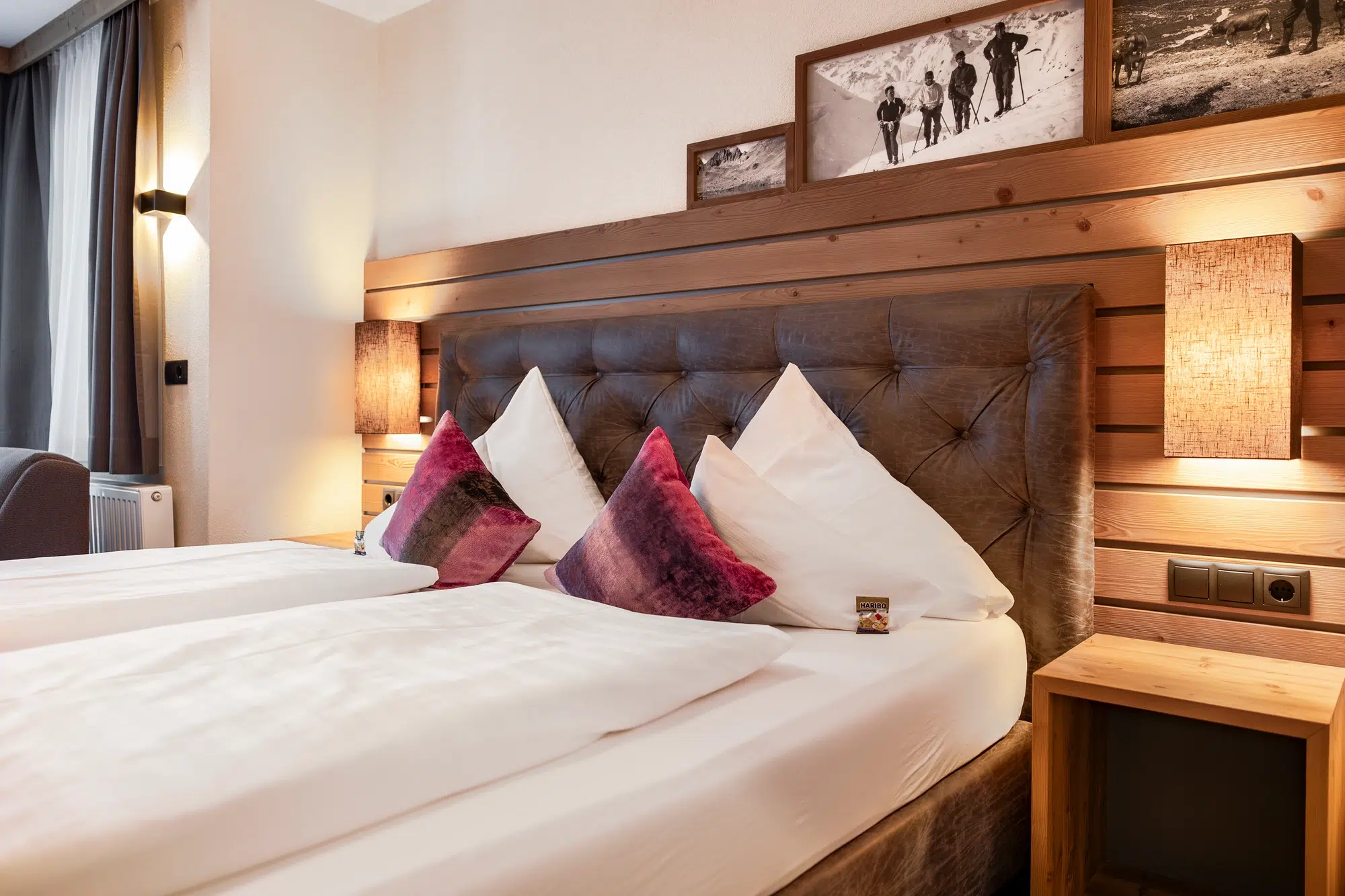 Gemütliches Zimmer mit Doppelbett, dekorativen Kissen und warmer Beleuchtung.