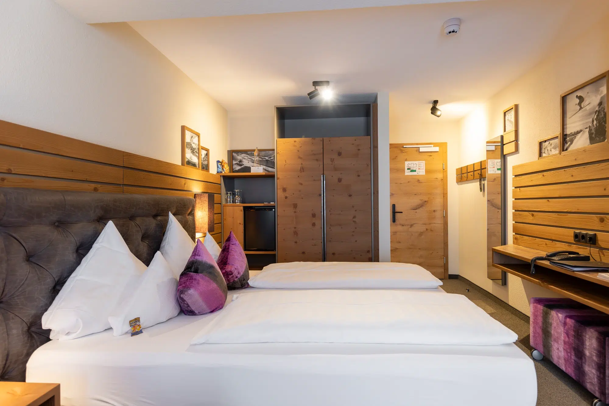 Modernes Zimmer mit zwei Einzelbetten, Holzakzenten und einem kleinen Arbeitsbereich in der Nähe des Eingangs.