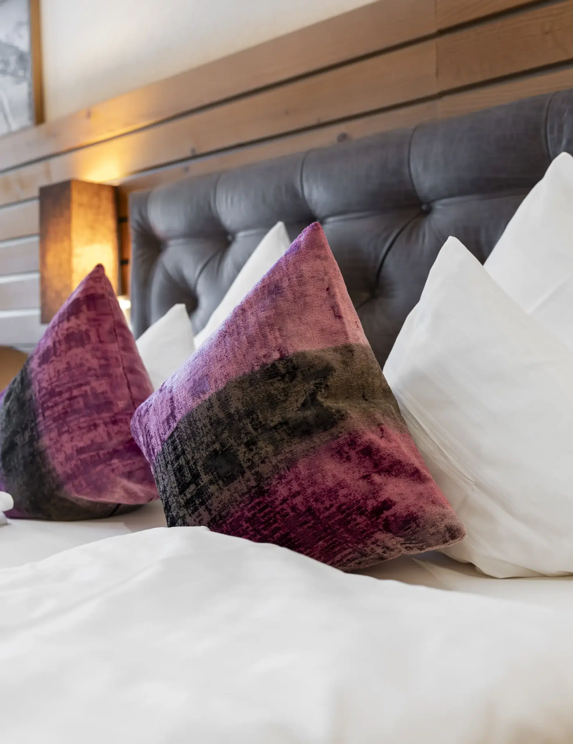 Zwei violette und schwarze Zierkissen verleihen diesem Zimmer mit frischer weißer Bettwäsche Eleganz.