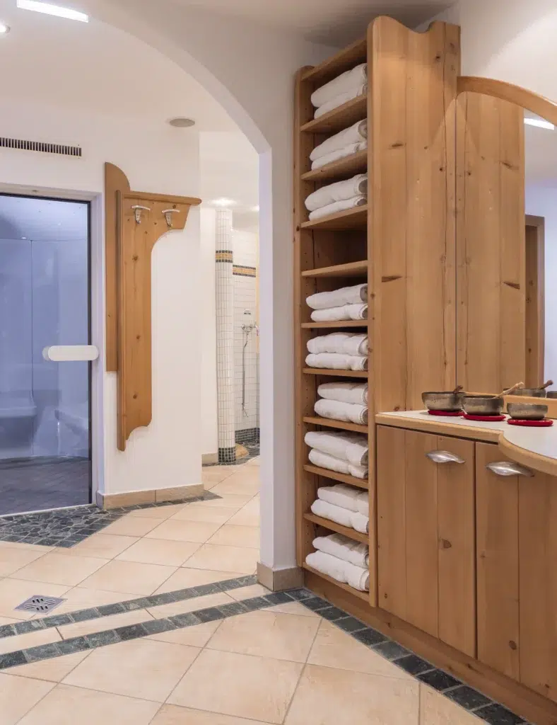 Mit weißen Handtüchern beladene Holzregale in einem sauberen, modernen Umkleideraum eines Wellnesshotels.