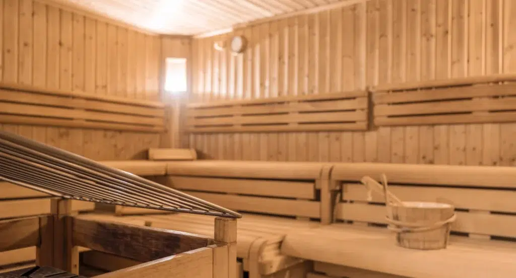 Innenansicht einer Holzsauna in einem Wellnesshotel mit Bänken, Ofen und Wassereimer.