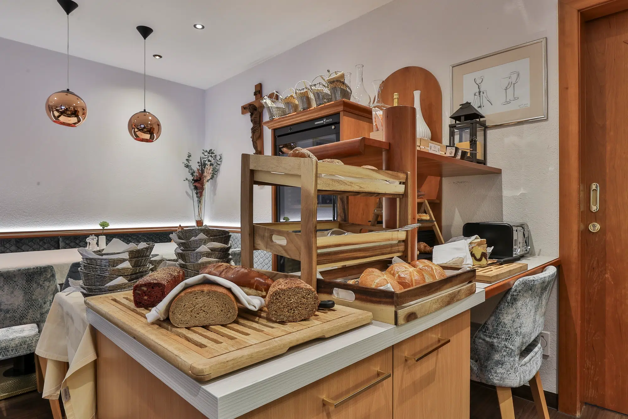 A restaurant breakfast buffet with bread, rolls, and sausages on wooden trays in a cozy dining area.
