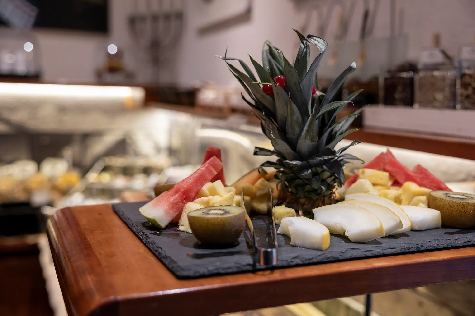 A restaurant platter with assorted fresh fruit slices, including pineapple, kiwi, and watermelon.
